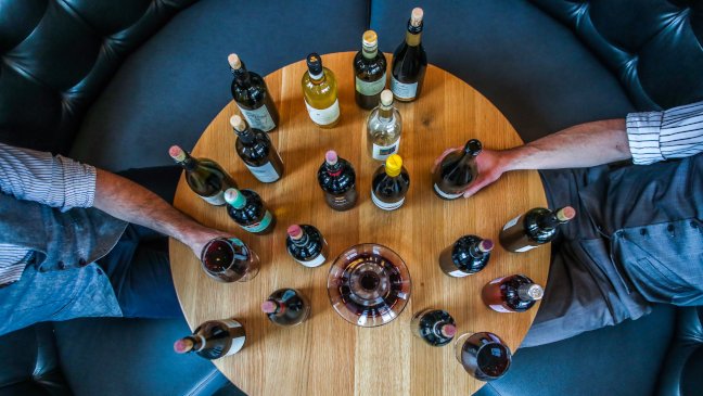 Ronde tafel vol wijnflessen met twee mensen